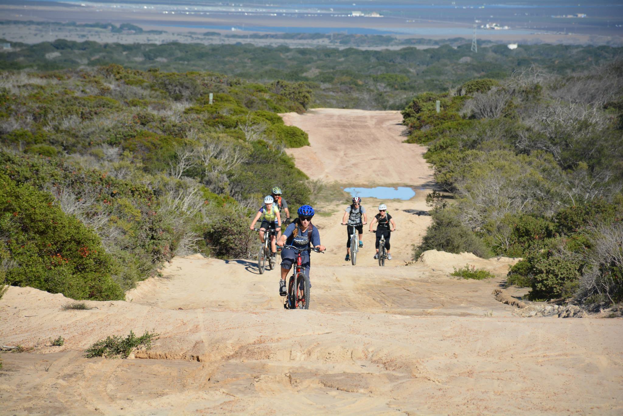 5 bikers riding up a dirt path