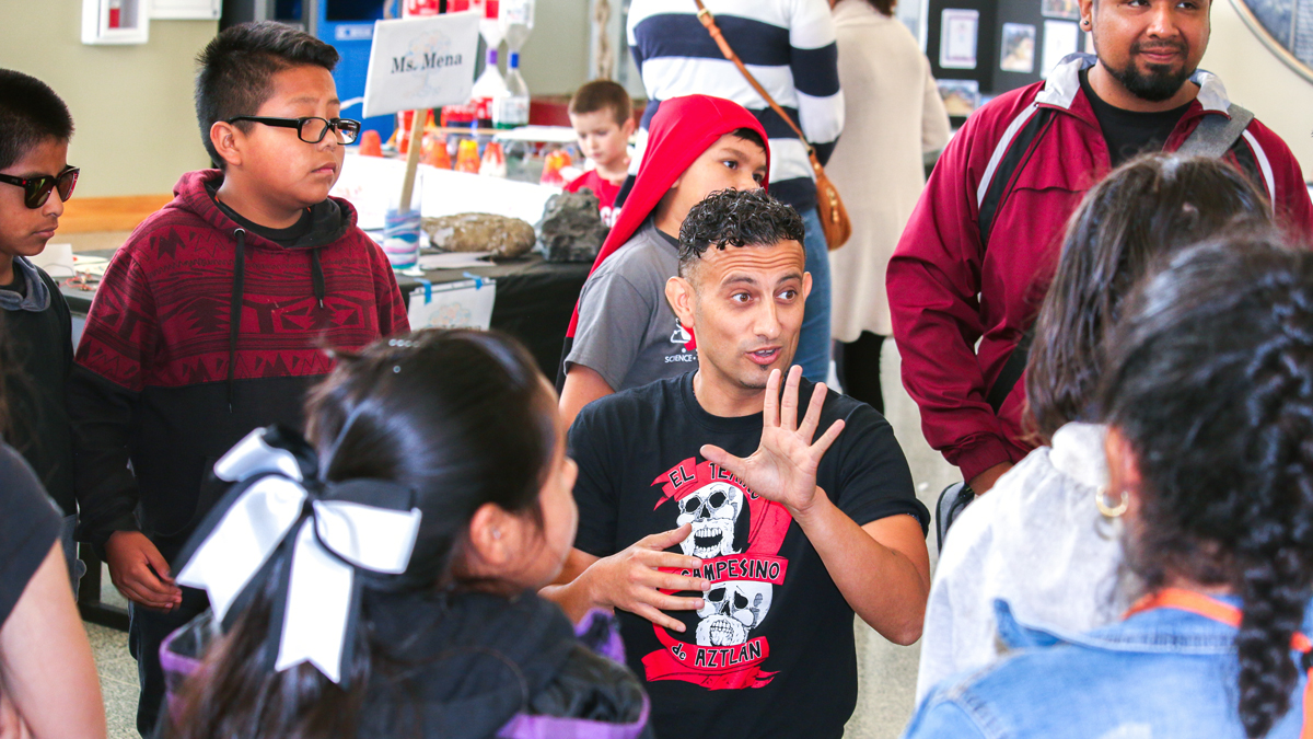 A teacher teaching students surrounding him