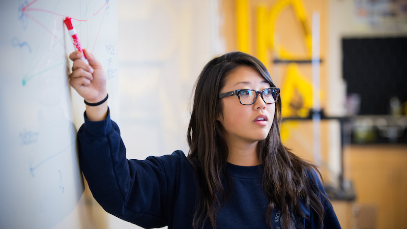 A student pointing on a white board