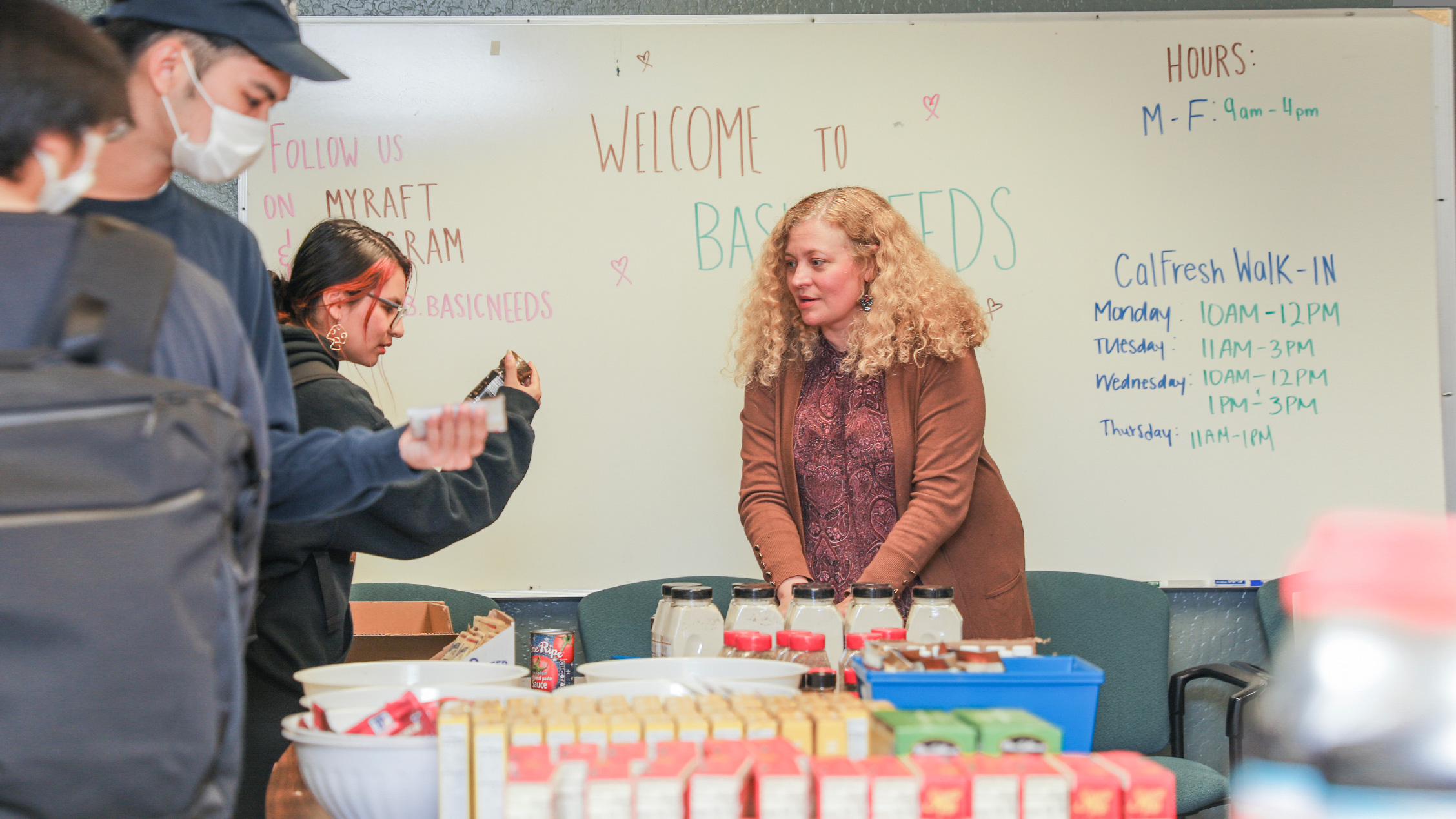 Care Manager Joanna Snawder-Manzo organizing food at the basic needs hub with students looking at what is available
