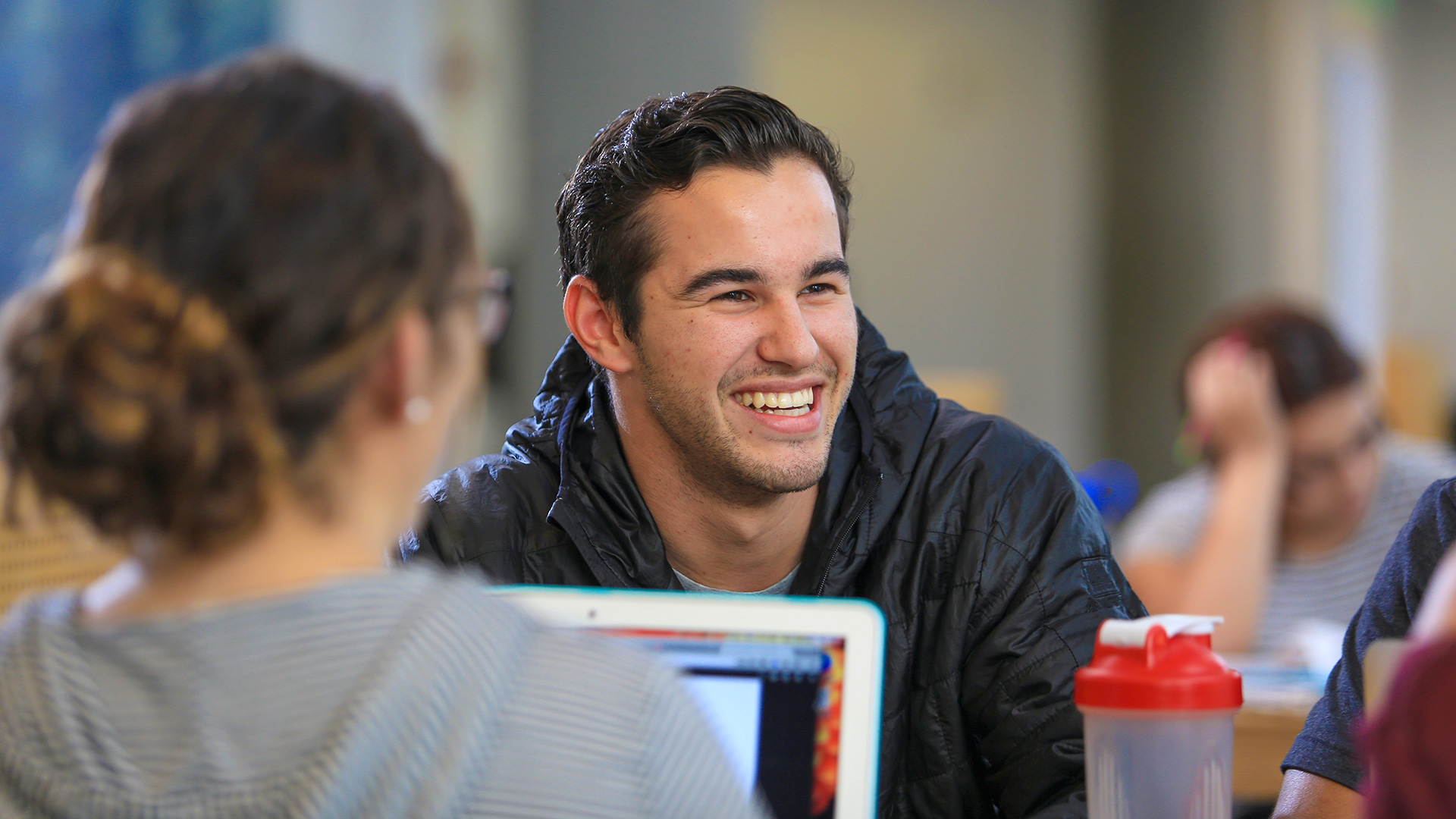 Student at the library smiling at peers