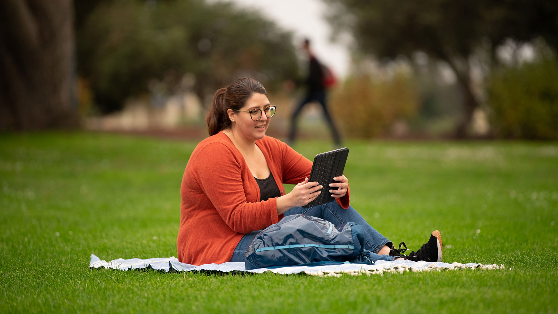 Student using tablet while sitting in the CSUMB Quad