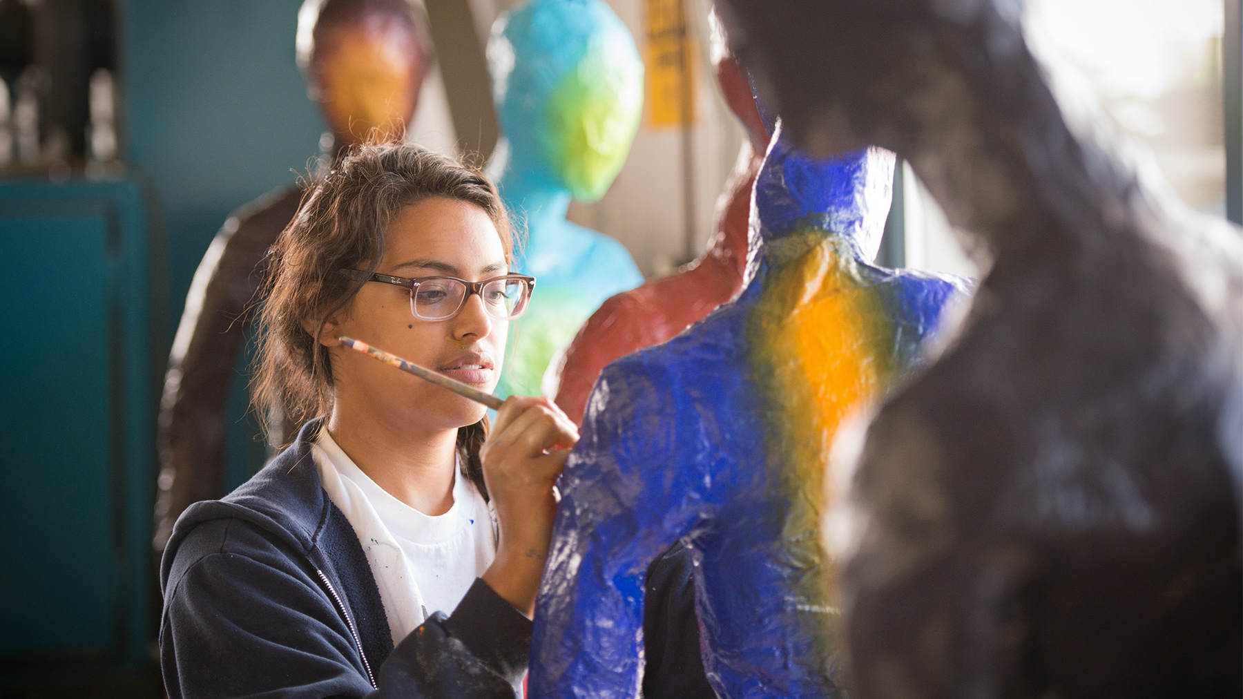 A CSUMB student painting on paper mache