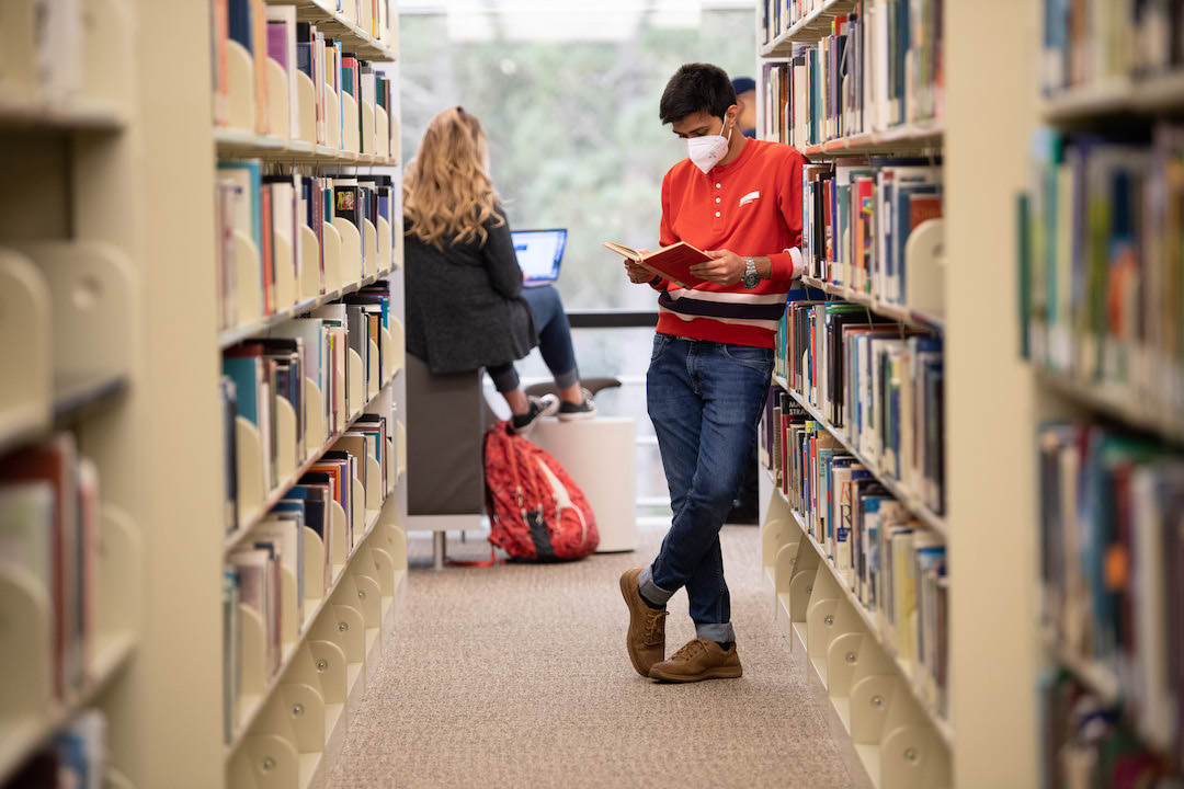 A CSUMB student reading a book in the library.