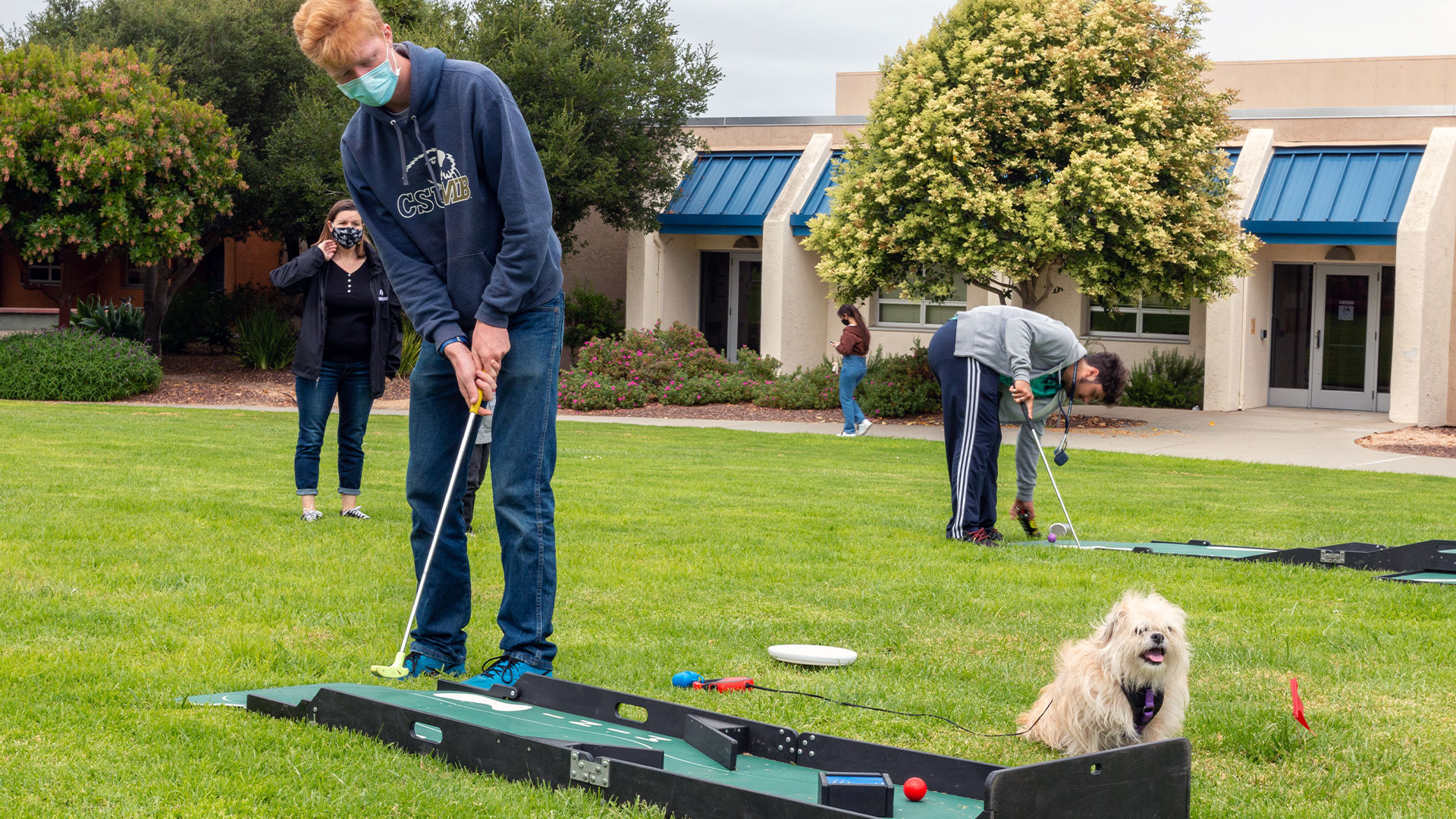 Photo: Masked students playing mini golf and a dog