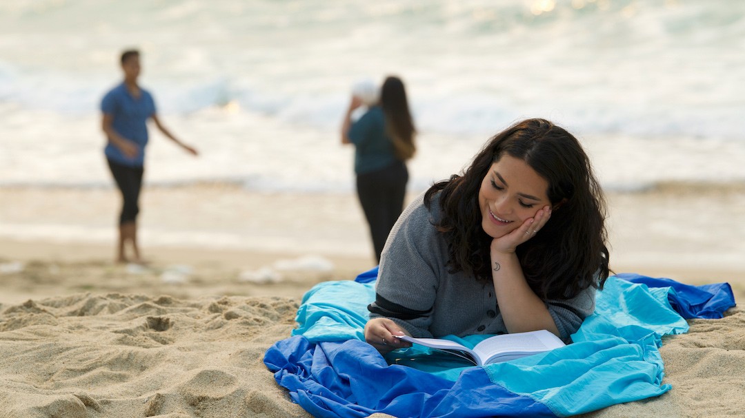 A CSUMB student reading at the beach