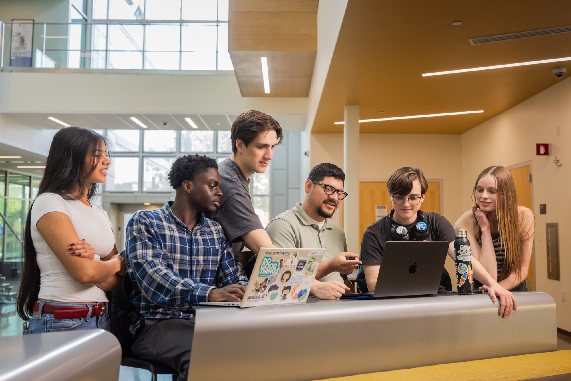 Group of students collaborating on a computer in the Business and Information Science building.