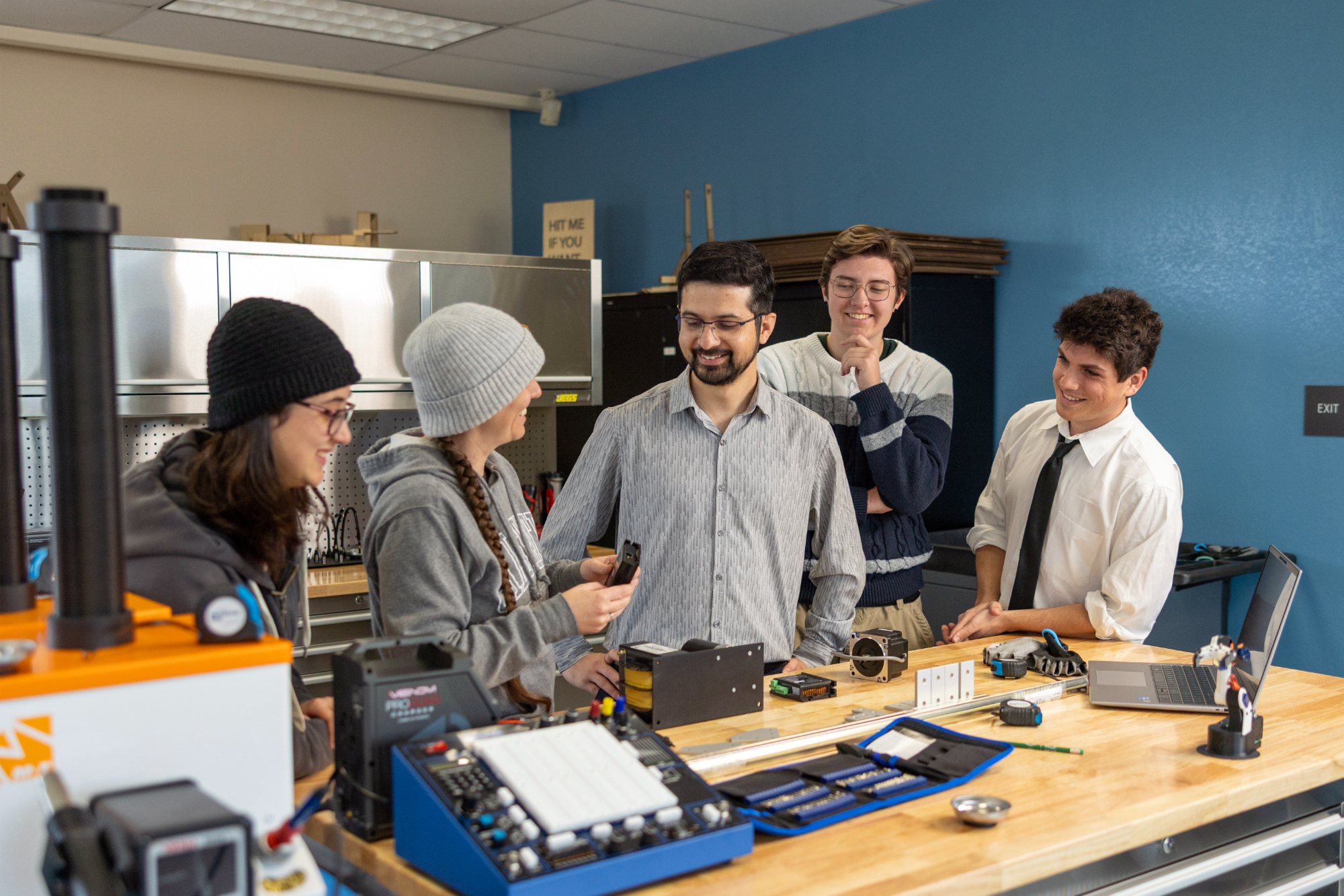 A group of four mechatronics students grouped around a professor