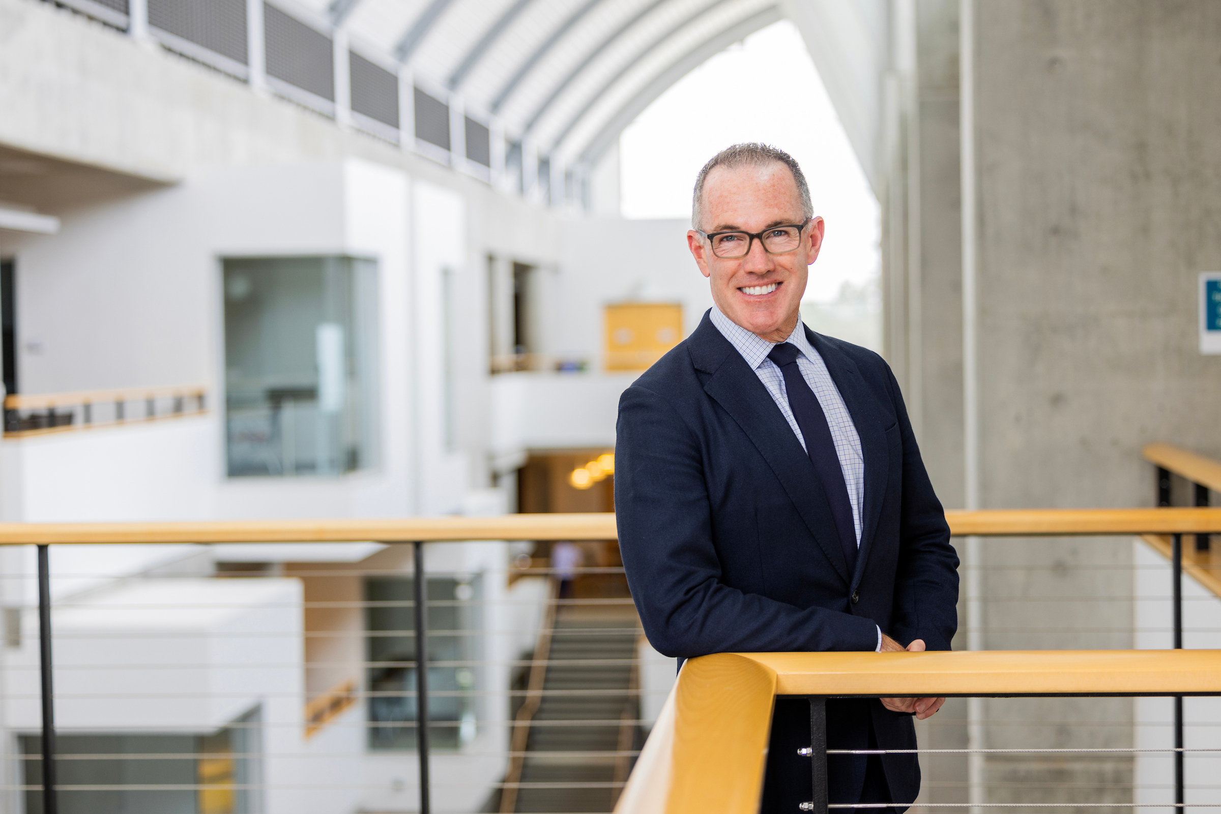 CSUMB Provost Andrew Lawson stands by a railing inside a modern campus building.