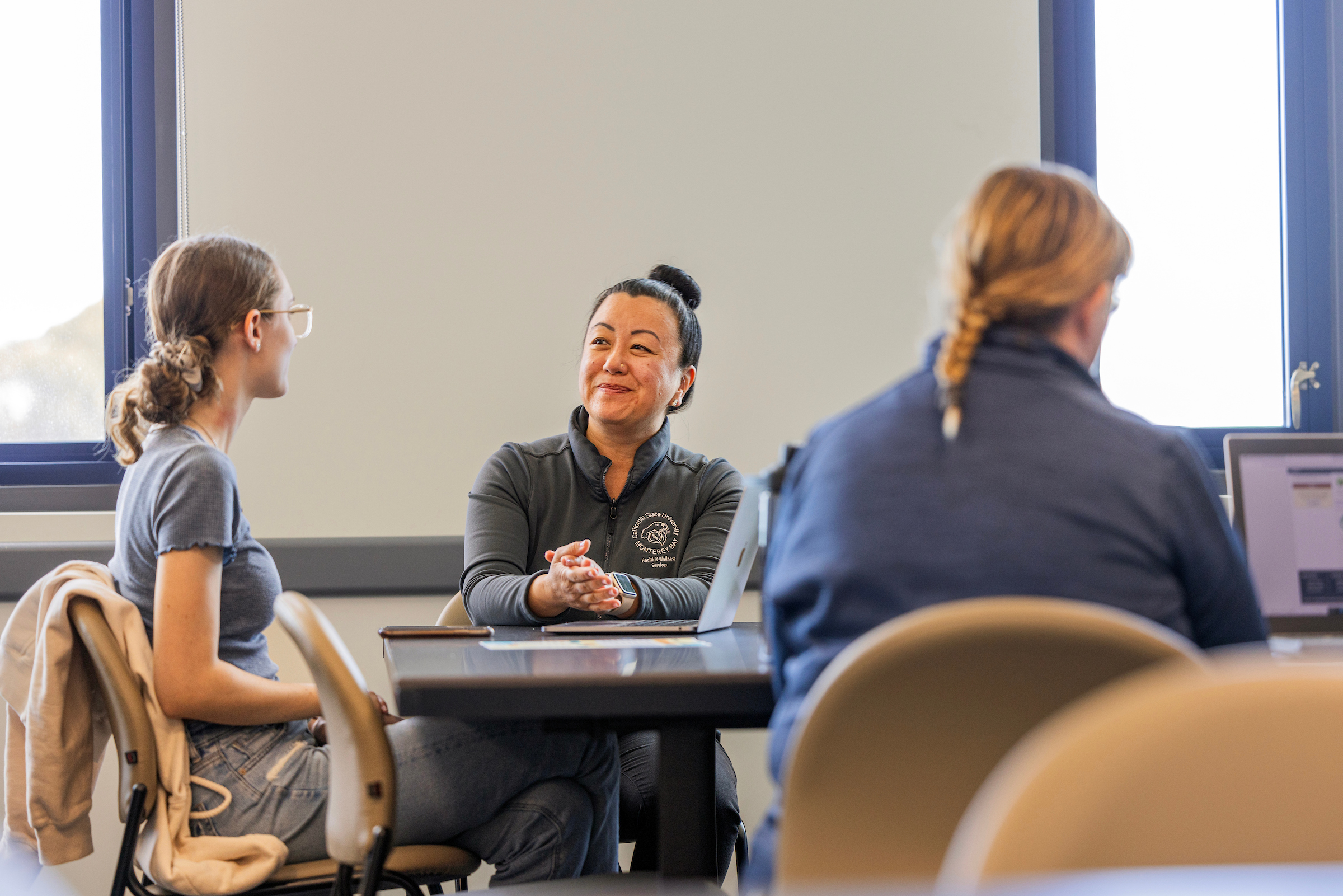 Three people sitting at tables with laptops