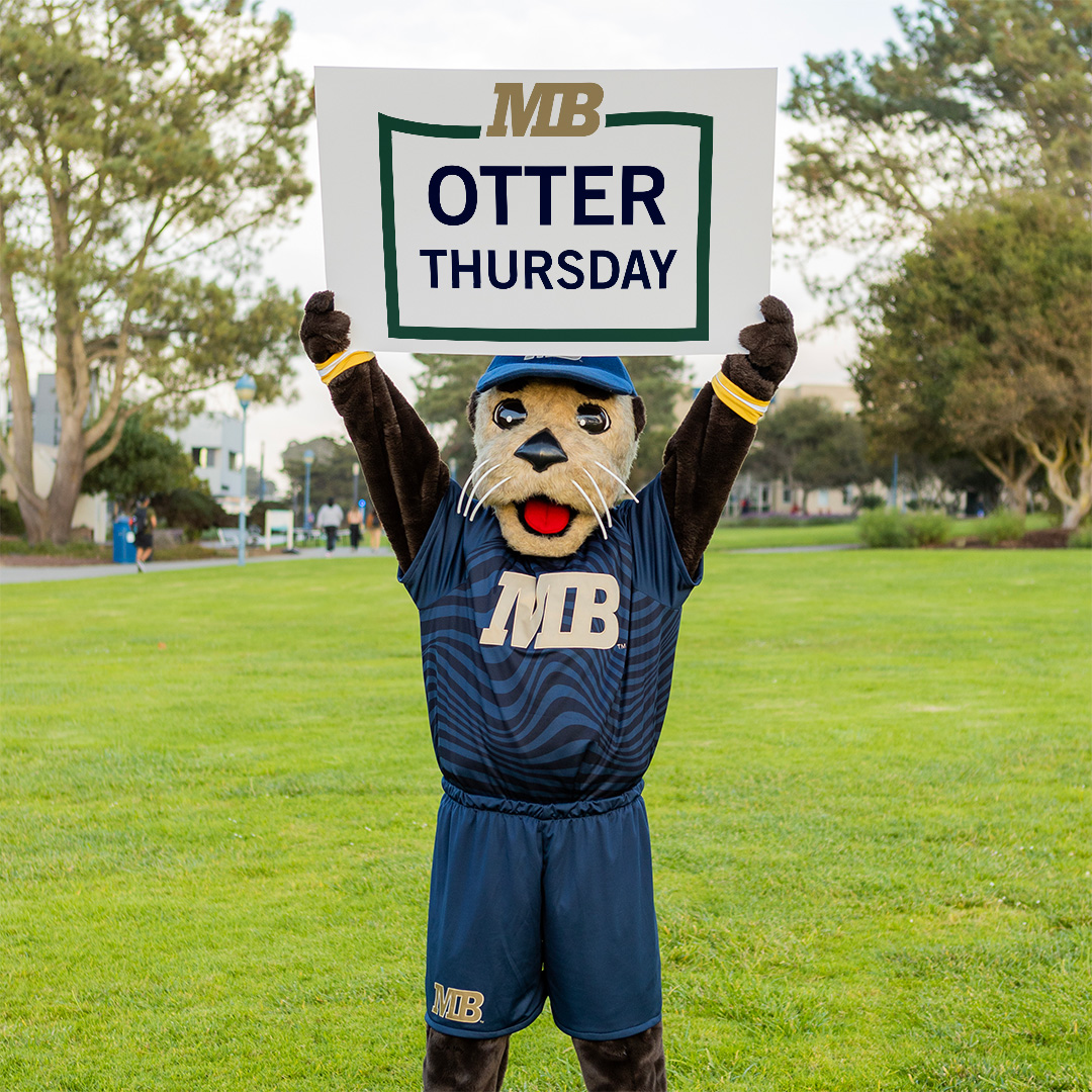 CSUMB Mascot Monte the Sea Otter outside holding a sign that reads