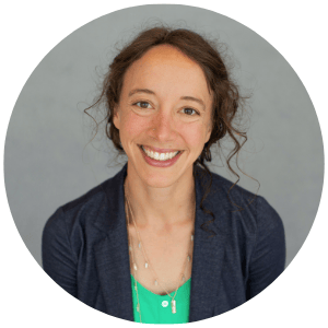 WOman with a welcoming smile dressed in a teal blouse and blue blazer