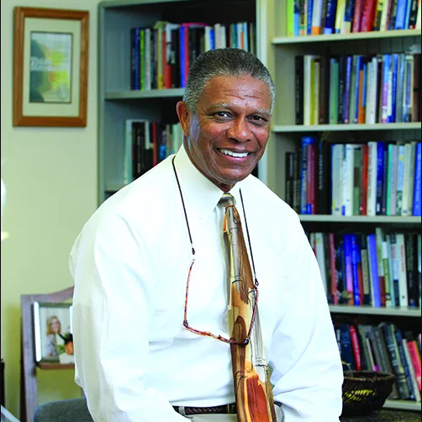 John Berteaux in front of bookcase full of books