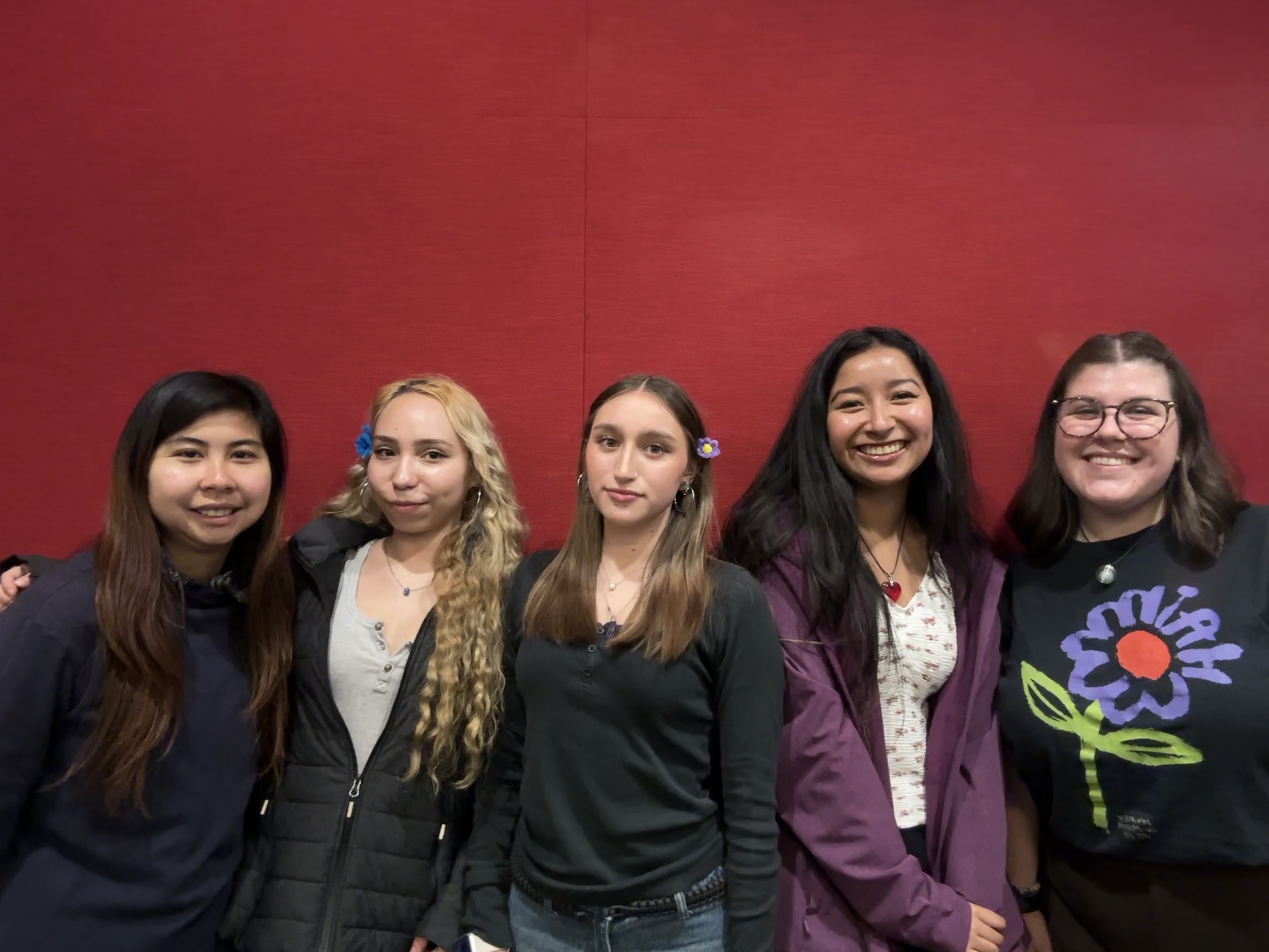 Students of Psych Society standing up against a red wall.