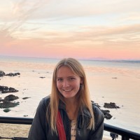 Shannon smiling for the camera with the sunset and ocean behind her