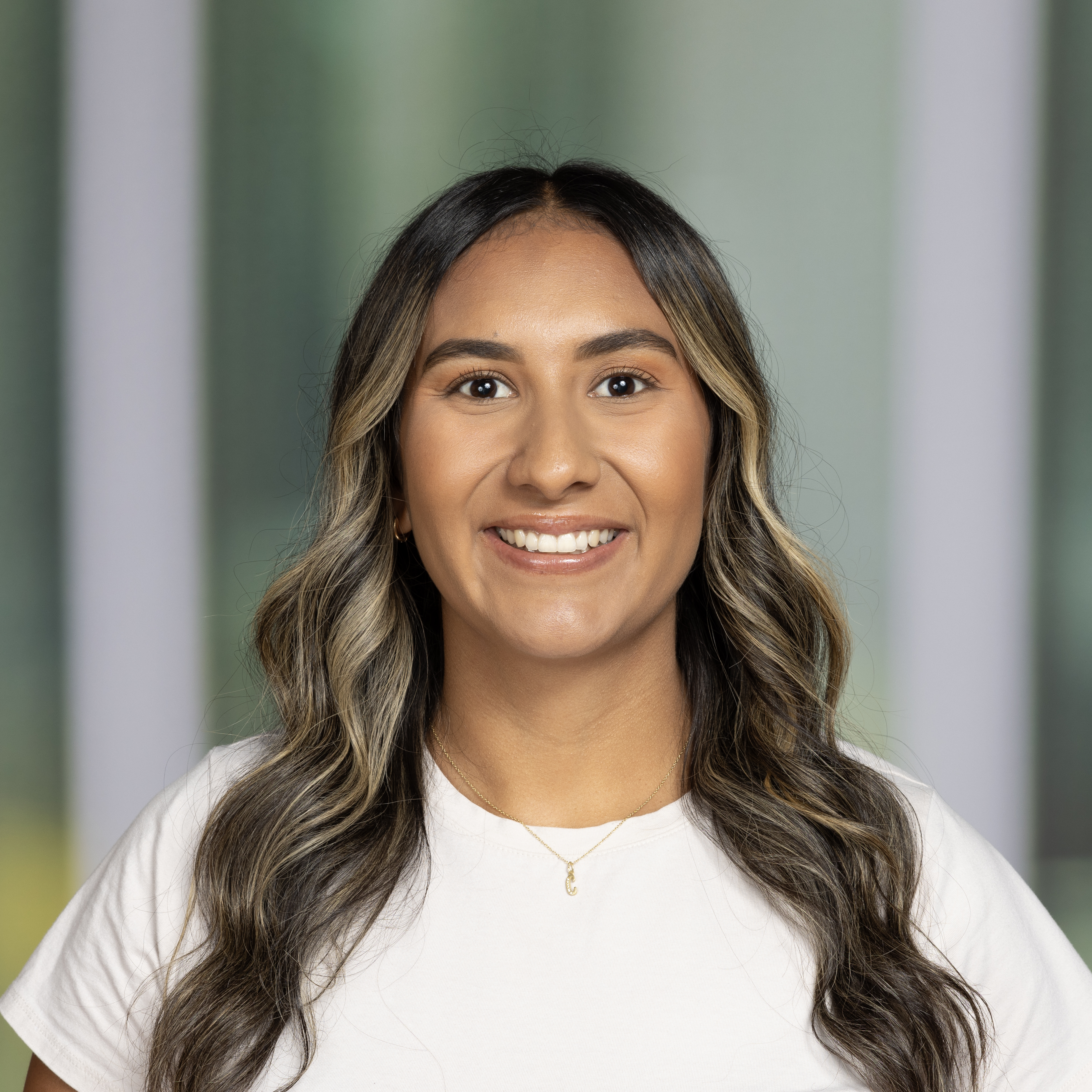 Carmen smiling and looking at the camera. The background behind Carmen is green