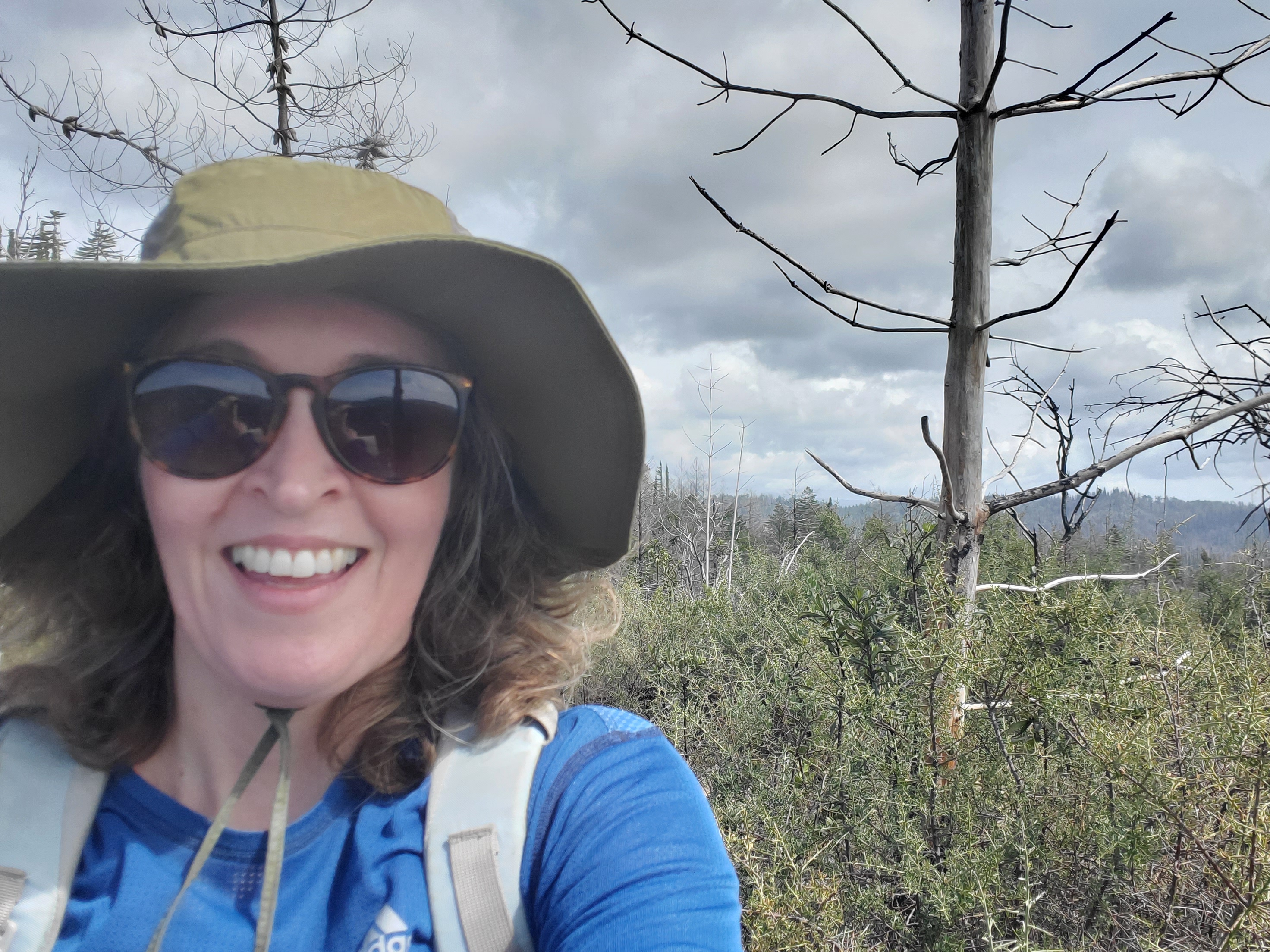 Erin is smiling and taking selfie while out hiking