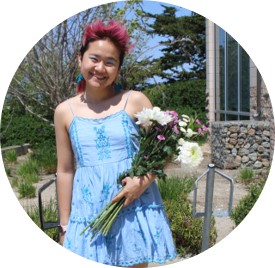 Wendy poses in a light blue dress with a bouquet of flowers