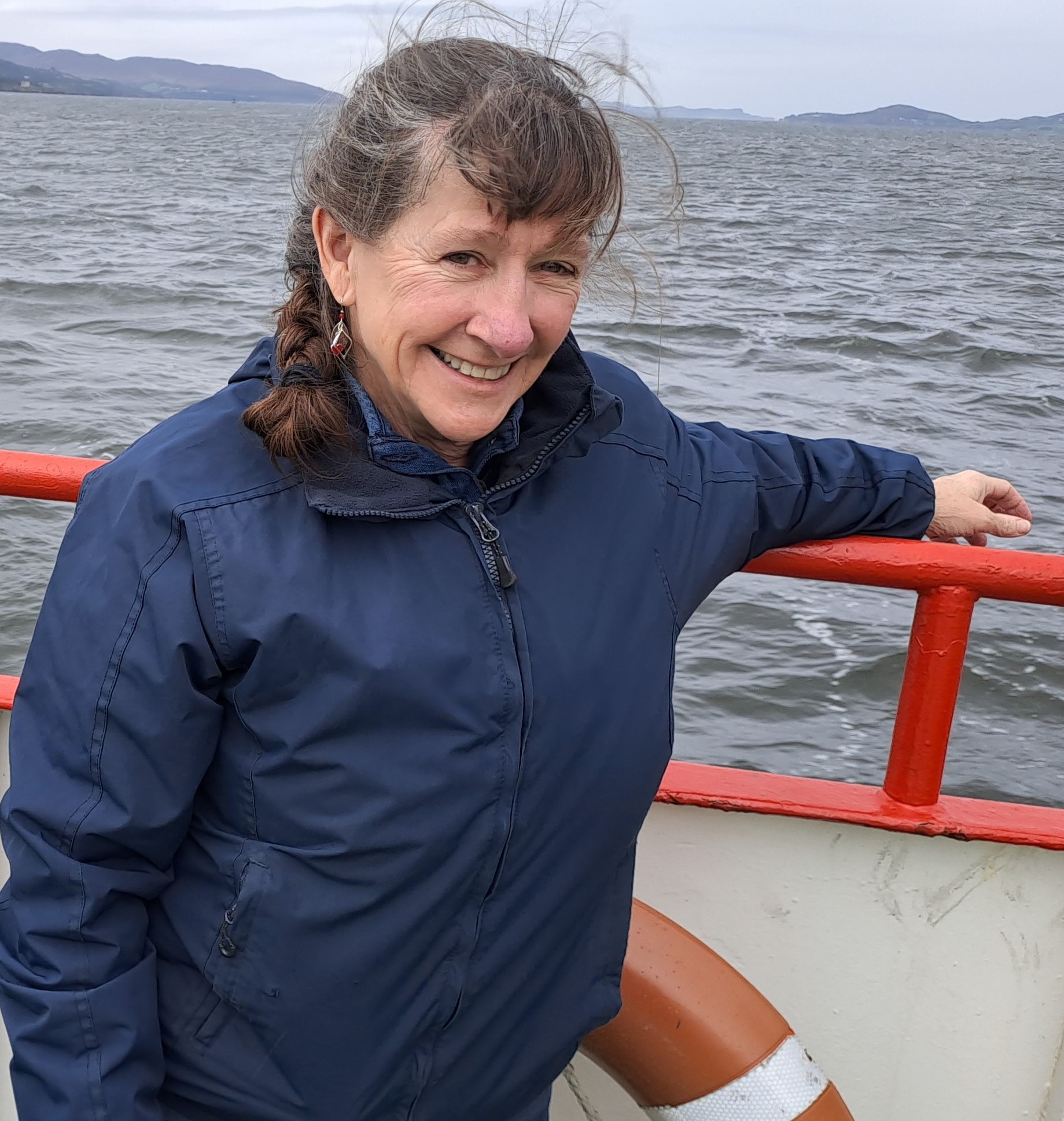 Monica smiling for the camera while holding onto a ship's railing.