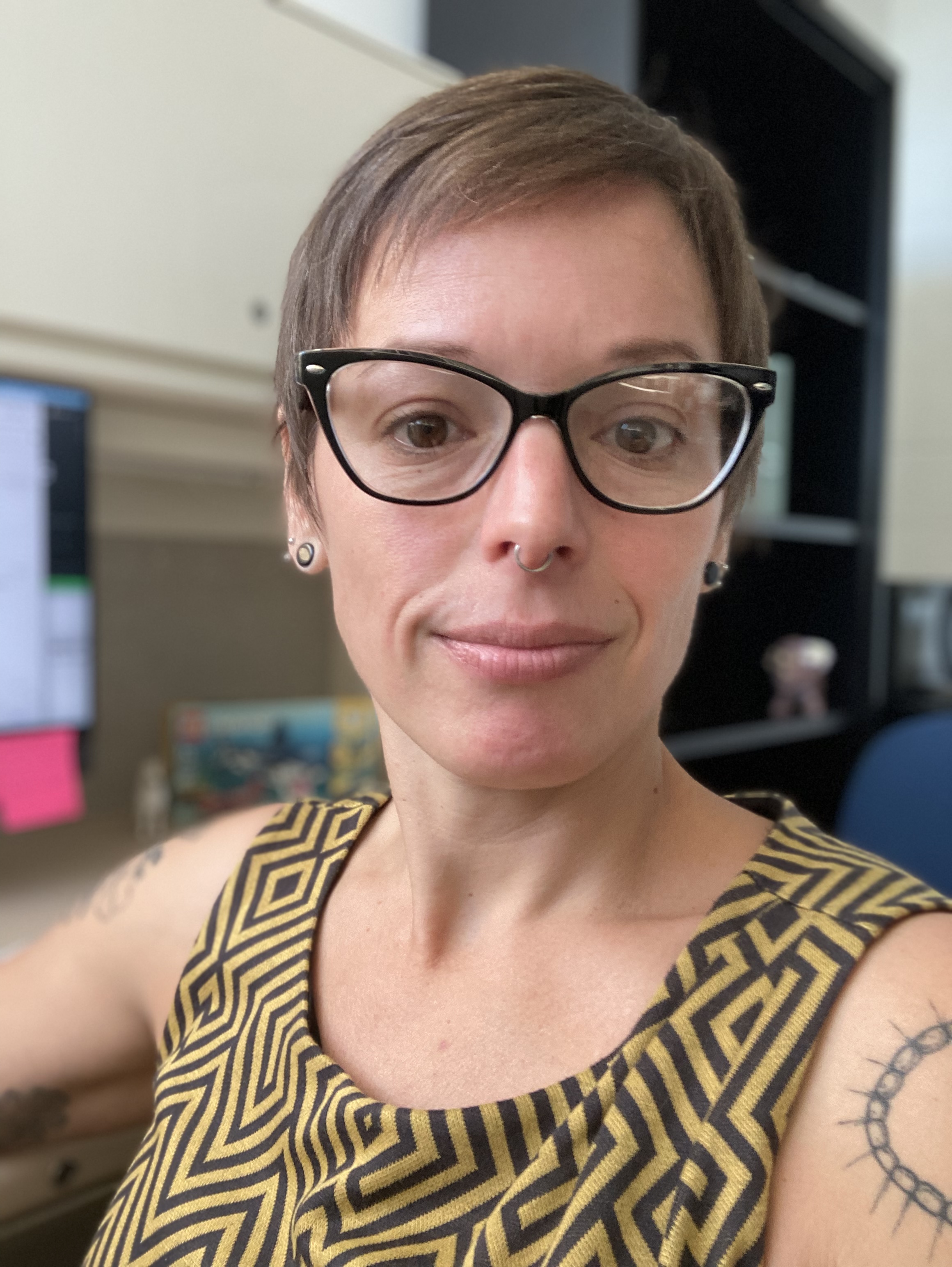 Lydia taking a selfie. She wears a black and yellow patterned tank top