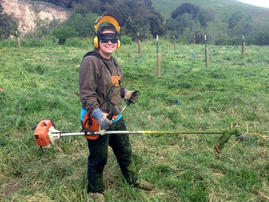 SIP student holds a weed whacker and gives a thumbs up