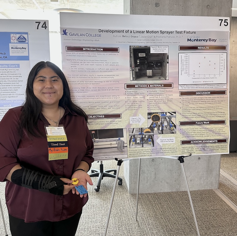 Female student standing next to research poster about linear motion sprayer test fixtures