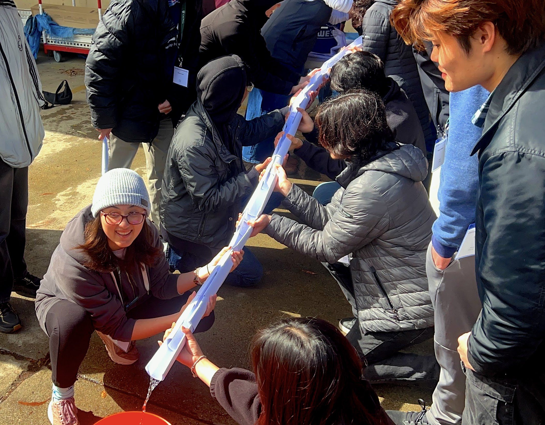 students funneling water to bucket
