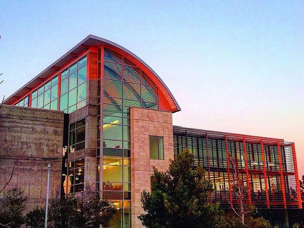 A colorful sunset reflects upon the top of the CSUMB Library