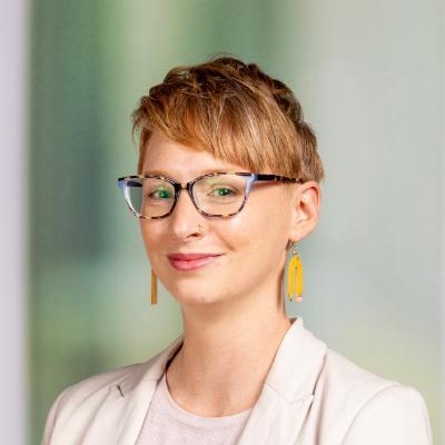 Woman with glasses and pencil earrings smiling at the camera