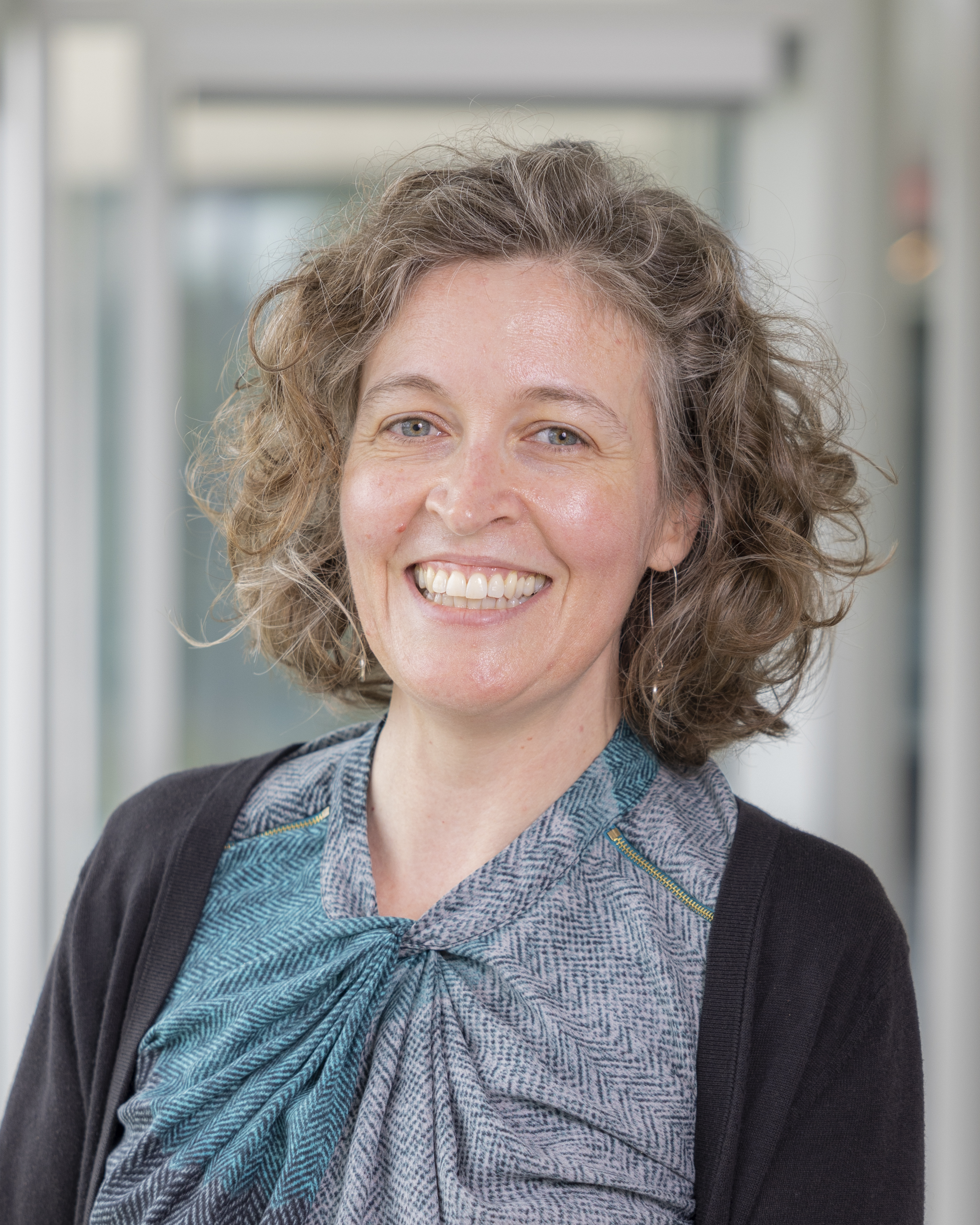 A woman with curly hair smiling at the camera