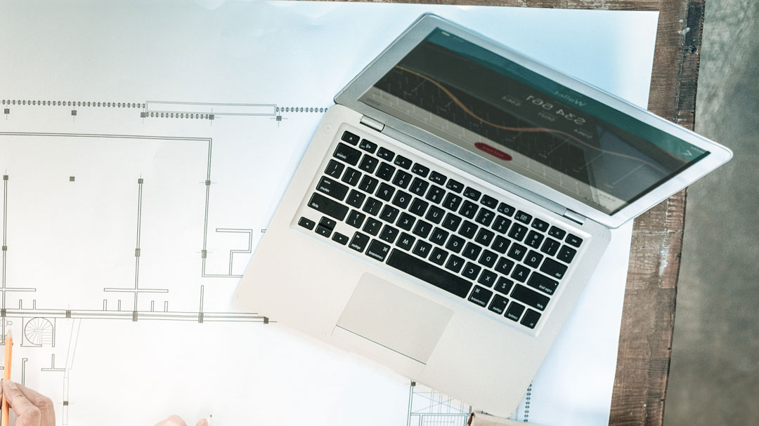 Laptop on top of a desk with blueprints