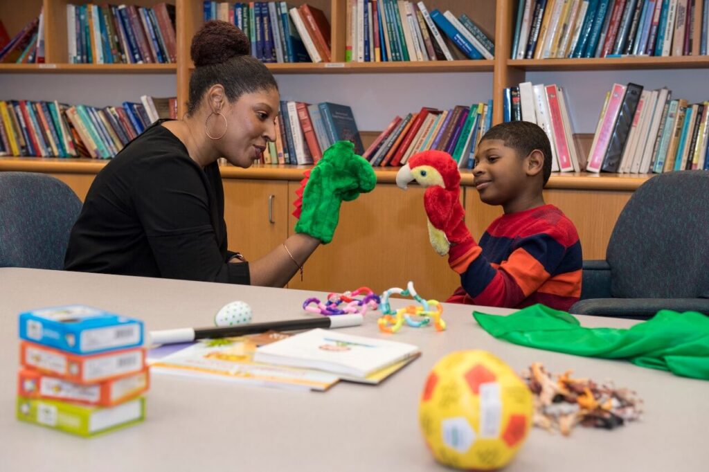 social worker with child playing with puppets