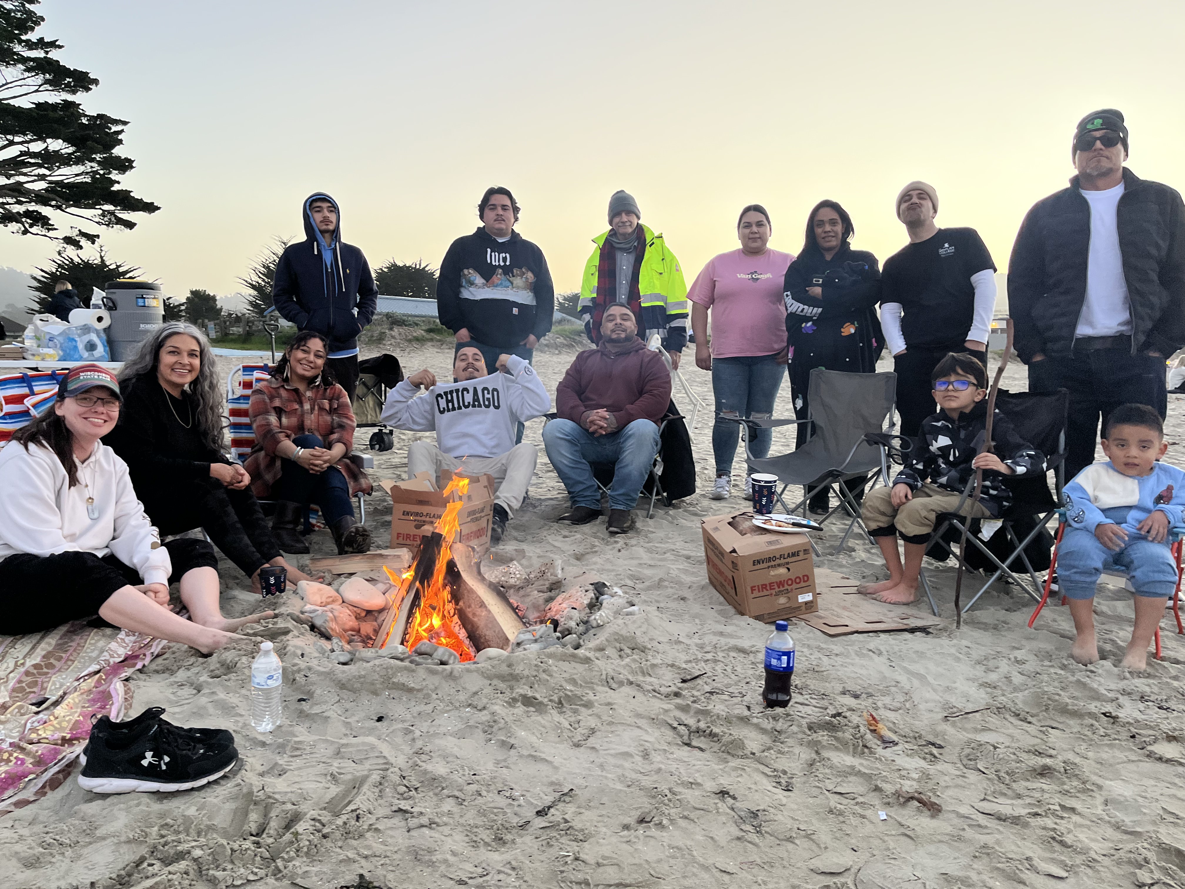 Project Rebound students sitting around a camp fire at del monte beach for community building event.