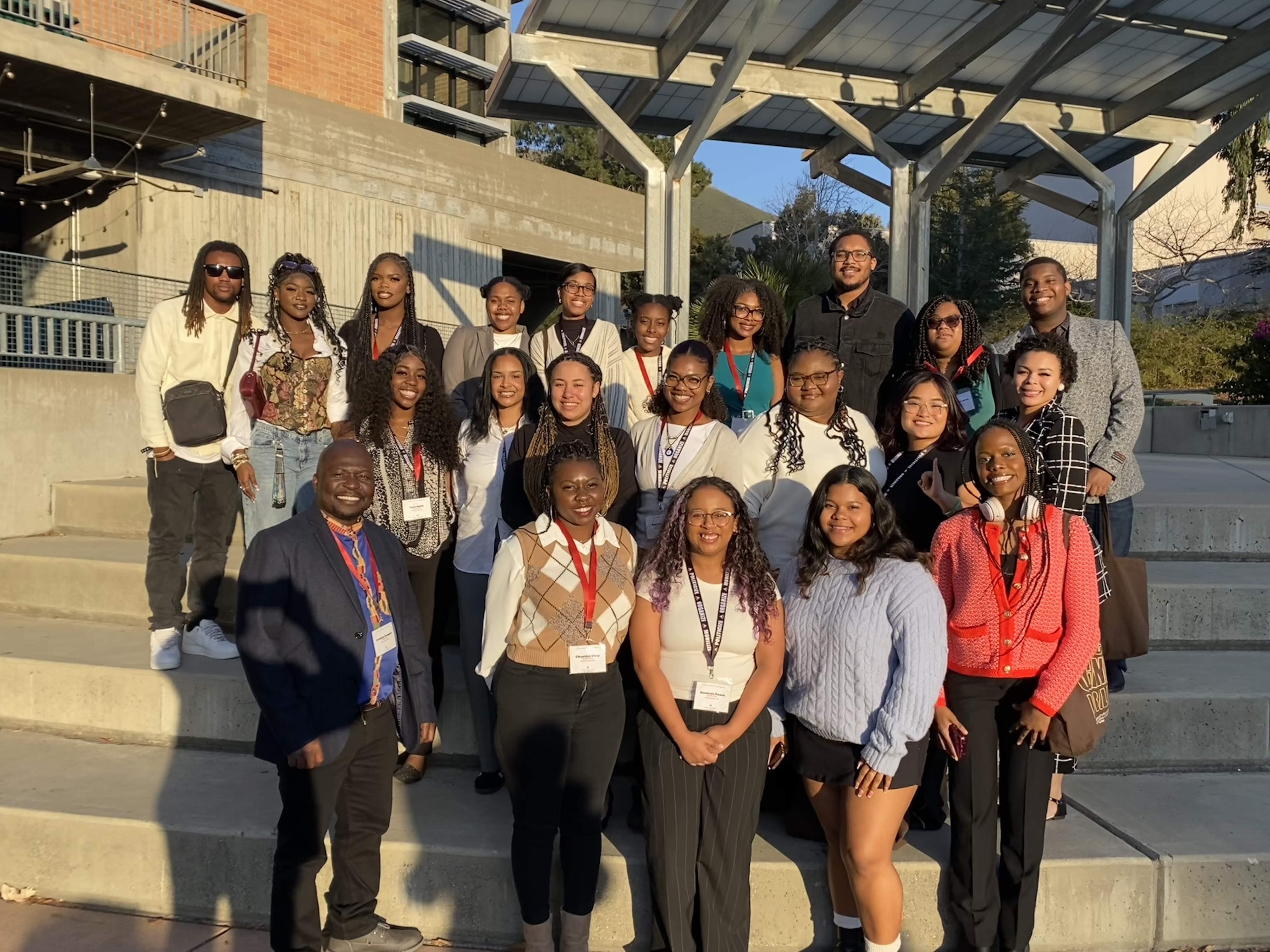 A group of students dressed in business casual attire standing on stair case smiling