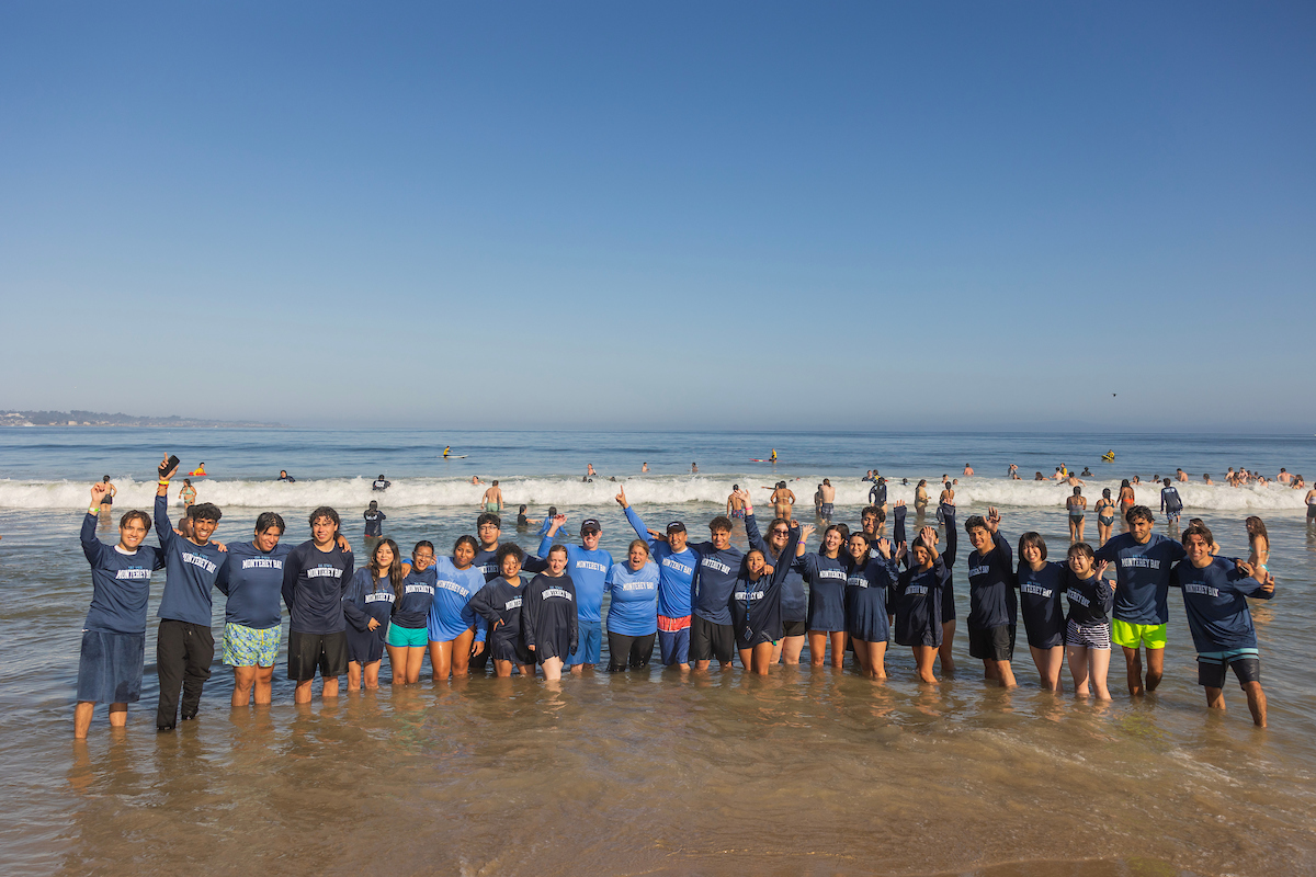 Lots of students and faculty standing in the water at the beach at The Plunge.