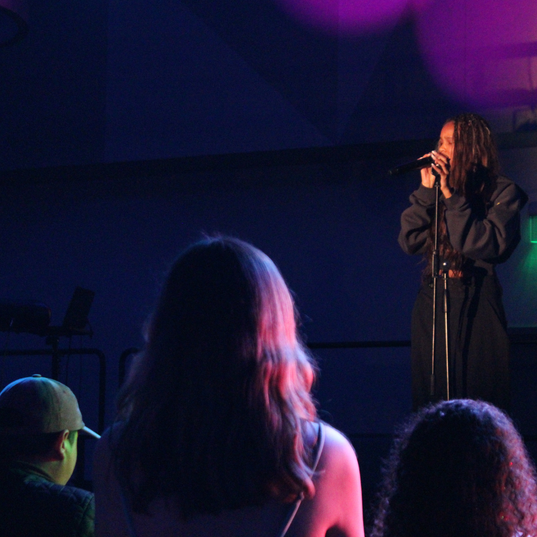 A performer performing their set on stage and students watching