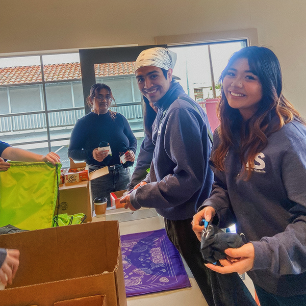 Image of three students in Community Engagement packaging bags for the homeless