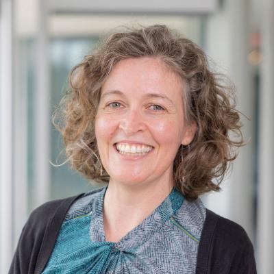 A woman with curly hair smiling at the camera