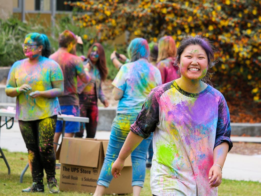 Happy students covered in colored paint chalk