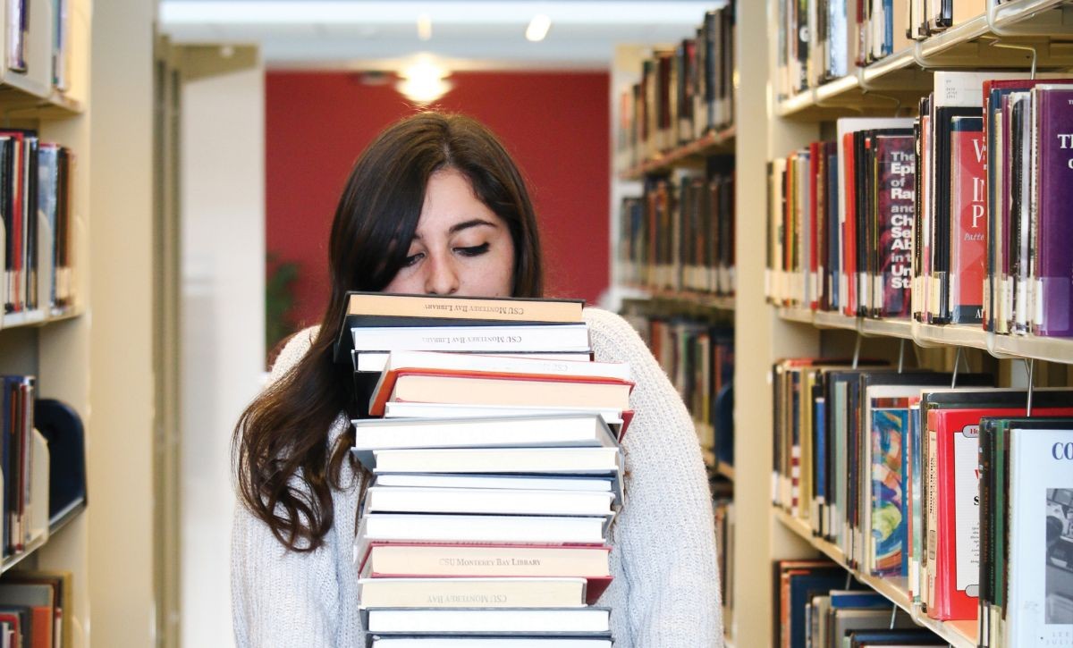 Student carrying a large stack of books.