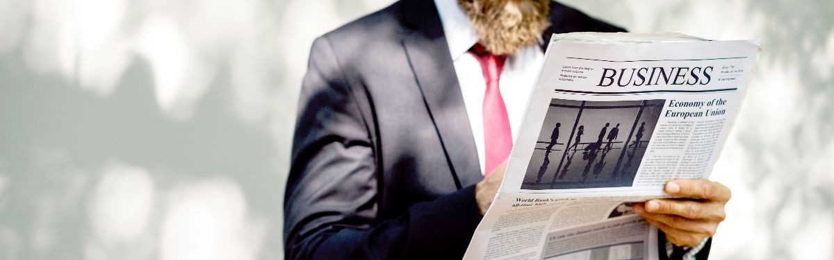 Photo of professionally dressed person reading business newspaper.