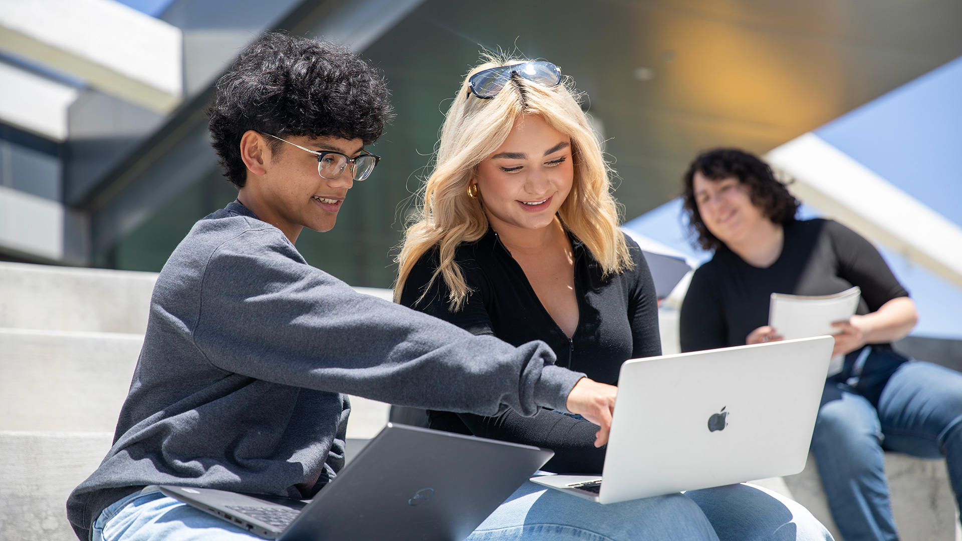 Two CSUMB students pointing at laptop
