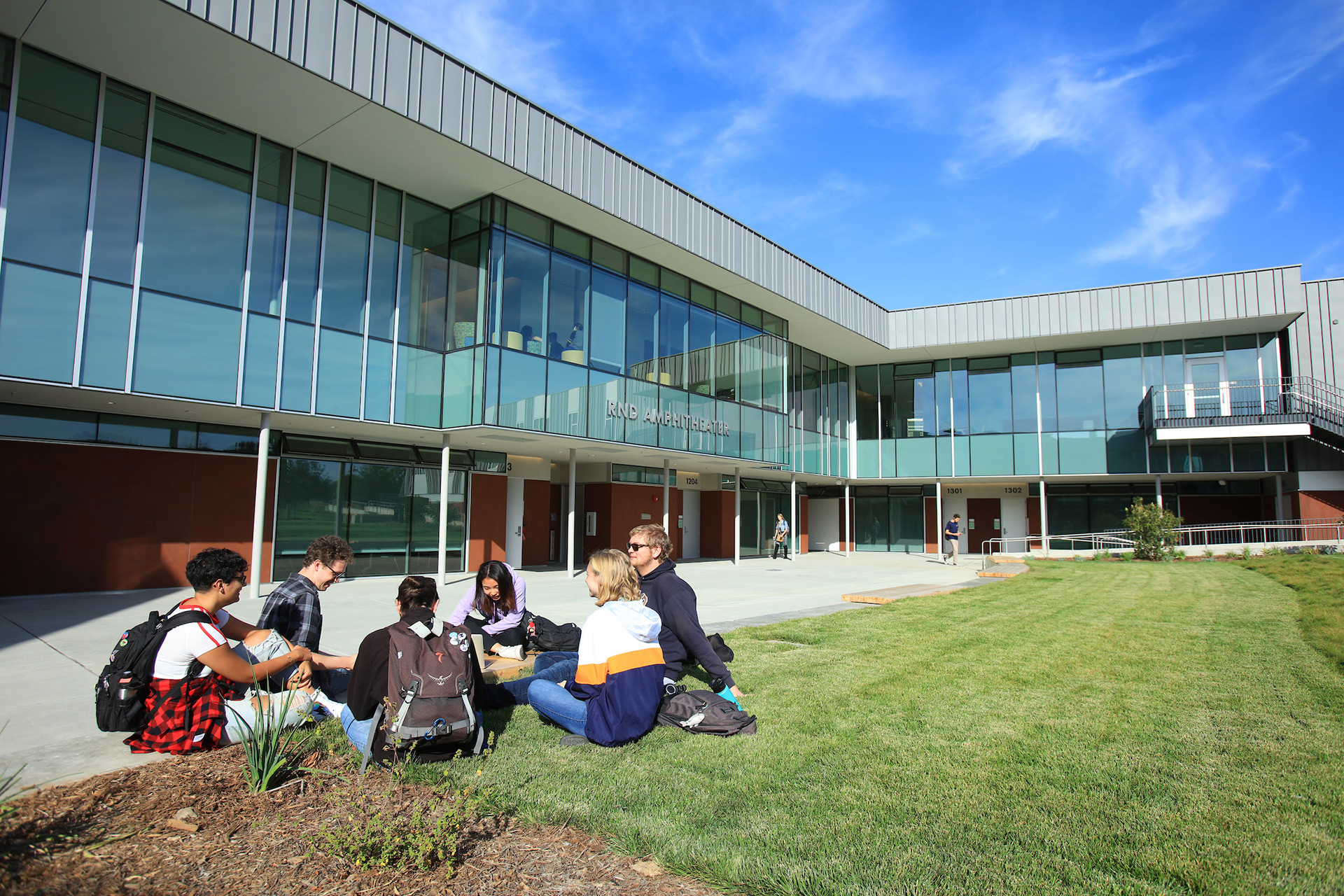 Student sitting in the grass are in front of RND Amphitheater