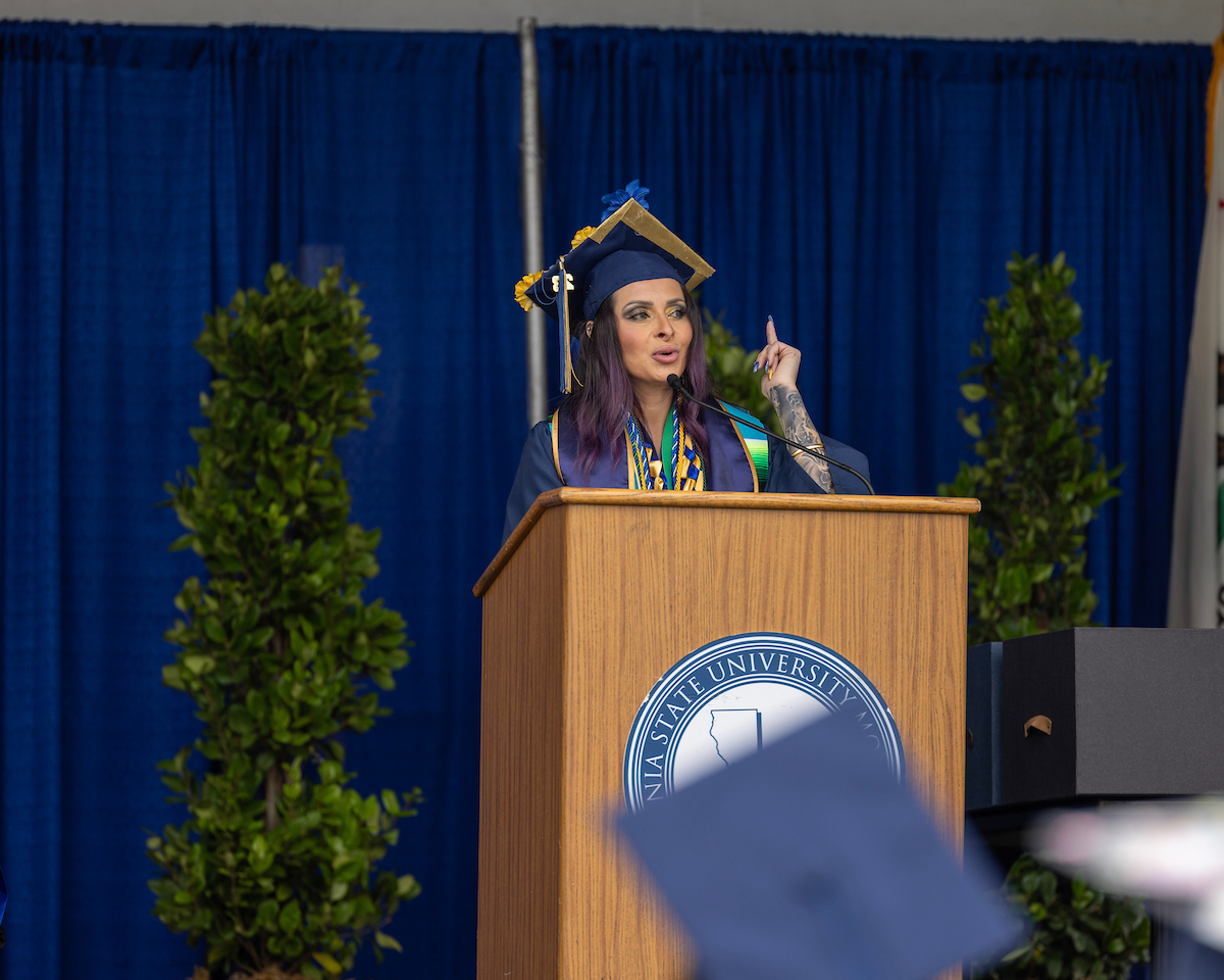 Graduate in cap and gown at podium