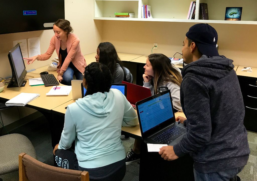 a group of students and Dr. Lovell in the lab looking at a computer screen