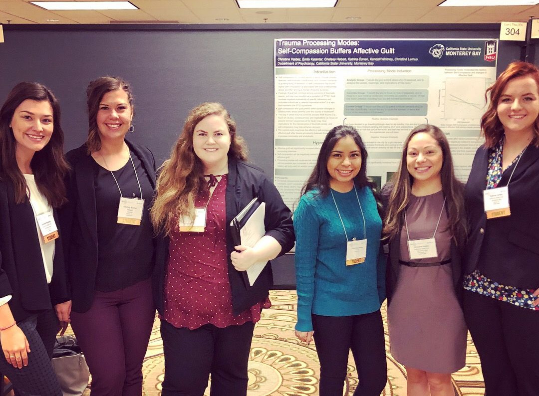 Students and Dr. Valdez standing in front of a research poster at a conference