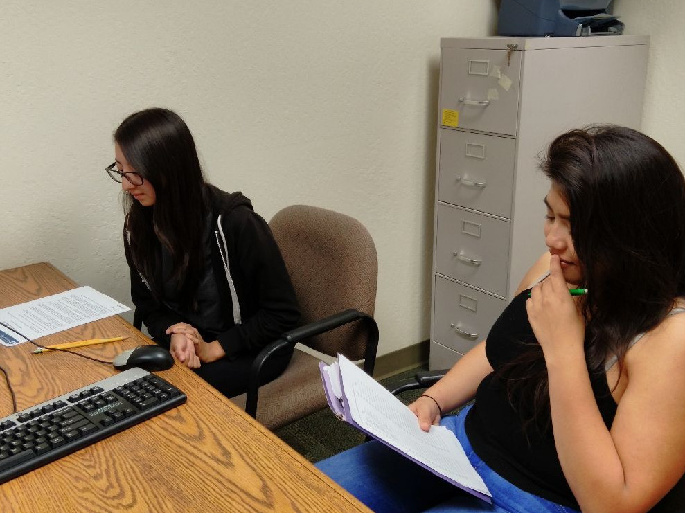 two students at a table looking at a computer screen in a research lab