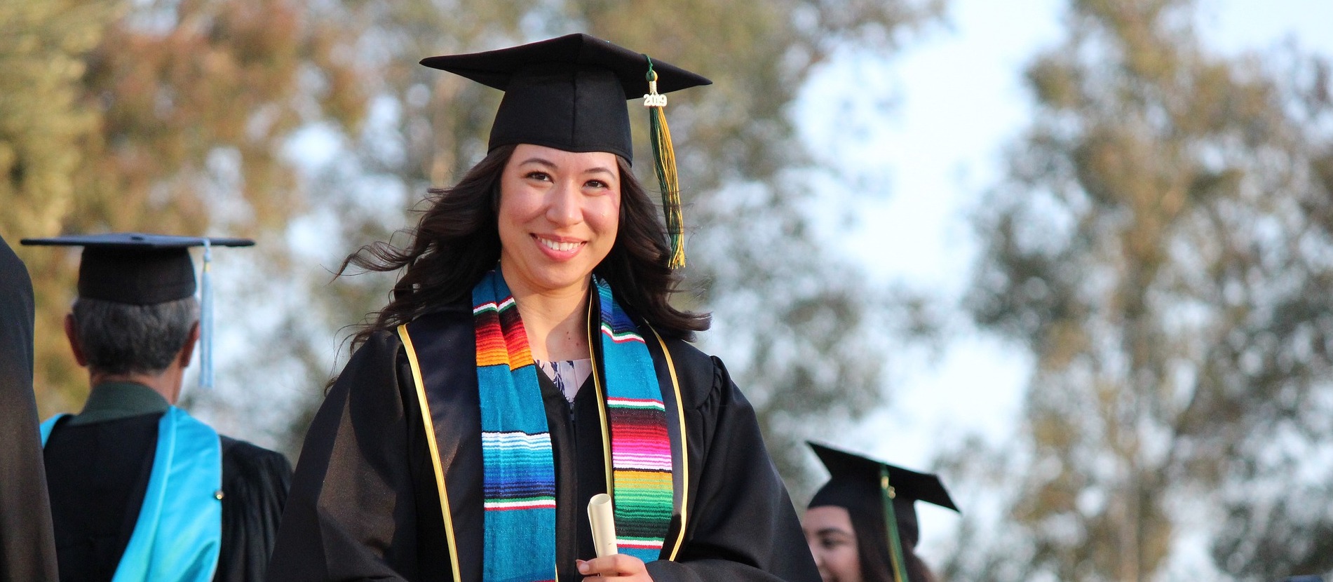 woman wearing regalia holding a diploma