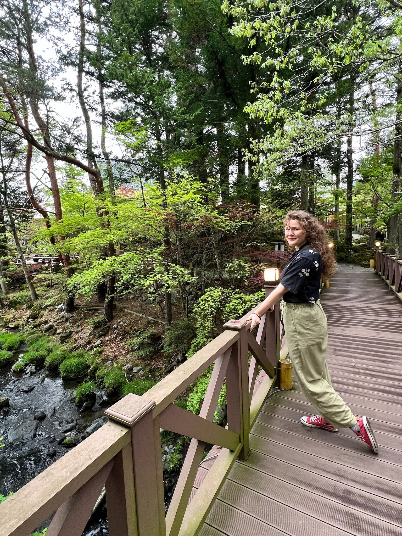 Alum standing on bridge in forested area