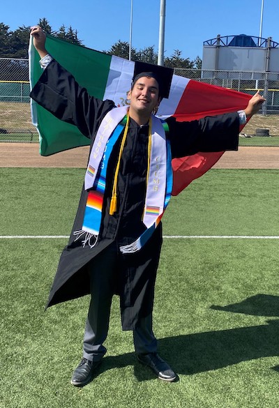 Lucas Bugarin holding Mexican flag at CSUMB graduation ceremony